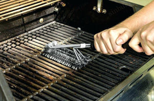 bbq grill being cleaned with a wire brush