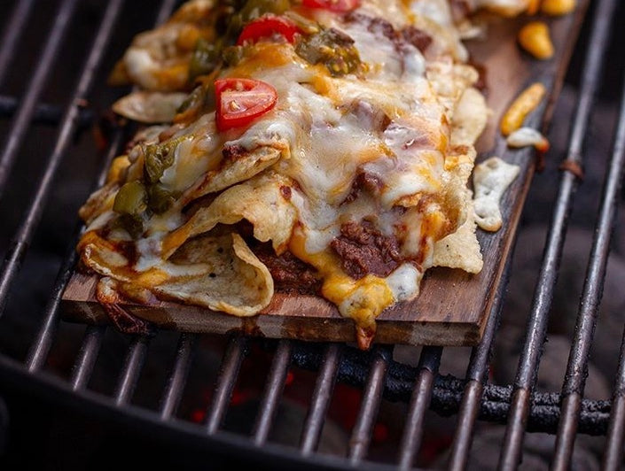 Nachos cooking on a wood grilling plank